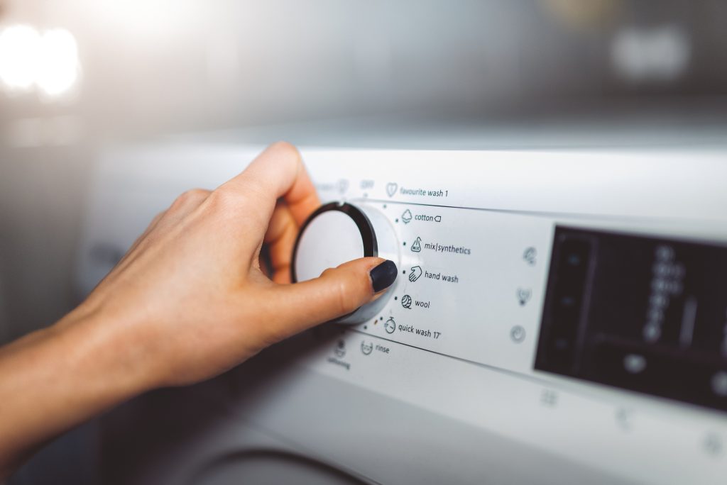 Woman turning dial on washing machine