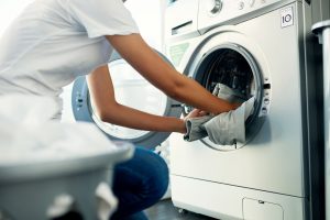 Woman putting clothes in washing machine with serial number on display