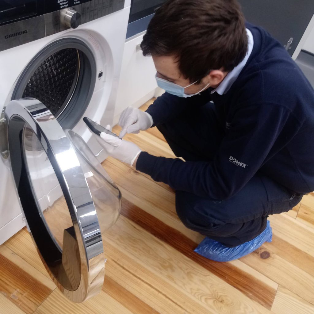 Domex engineer inspecting washing machine in PPE COVID-19 safety precautions